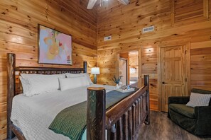 Une chambre à coucher dans une cabane en bois, avec un lit, une table de chevet, une lampe, une chaise et une porte.