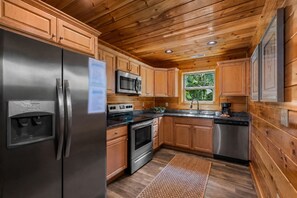 Cozinha compacta com armários de madeira, eletrodomésticos de aço inoxidável e uma janela que oferece iluminação natural.