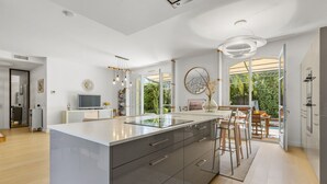 Eine moderne Küche mit einer großen Kochinsel, Barhocker und Blick ins Freie.