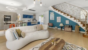 Ein modernes Wohnzimmer mit einem weißen Sofa, einem Holztisch und einer Treppe mit aufwendiger Geländerarbeit.