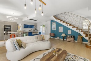 A modern living space with a white sofa, wooden coffee table, and a staircase with ornate railings. - Villa Jasmin | French Riviera Retreat (Vence)