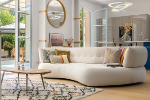Un salon moderne avec un canapé blanc, une table basse en bois et un tapis à motifs.