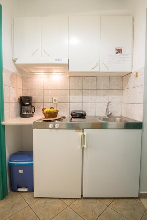 Eine kleine Küche mit weißen Schränken, einer Kaffeemaschine, einem Toaster und einem kleinen Kühlschrank.
