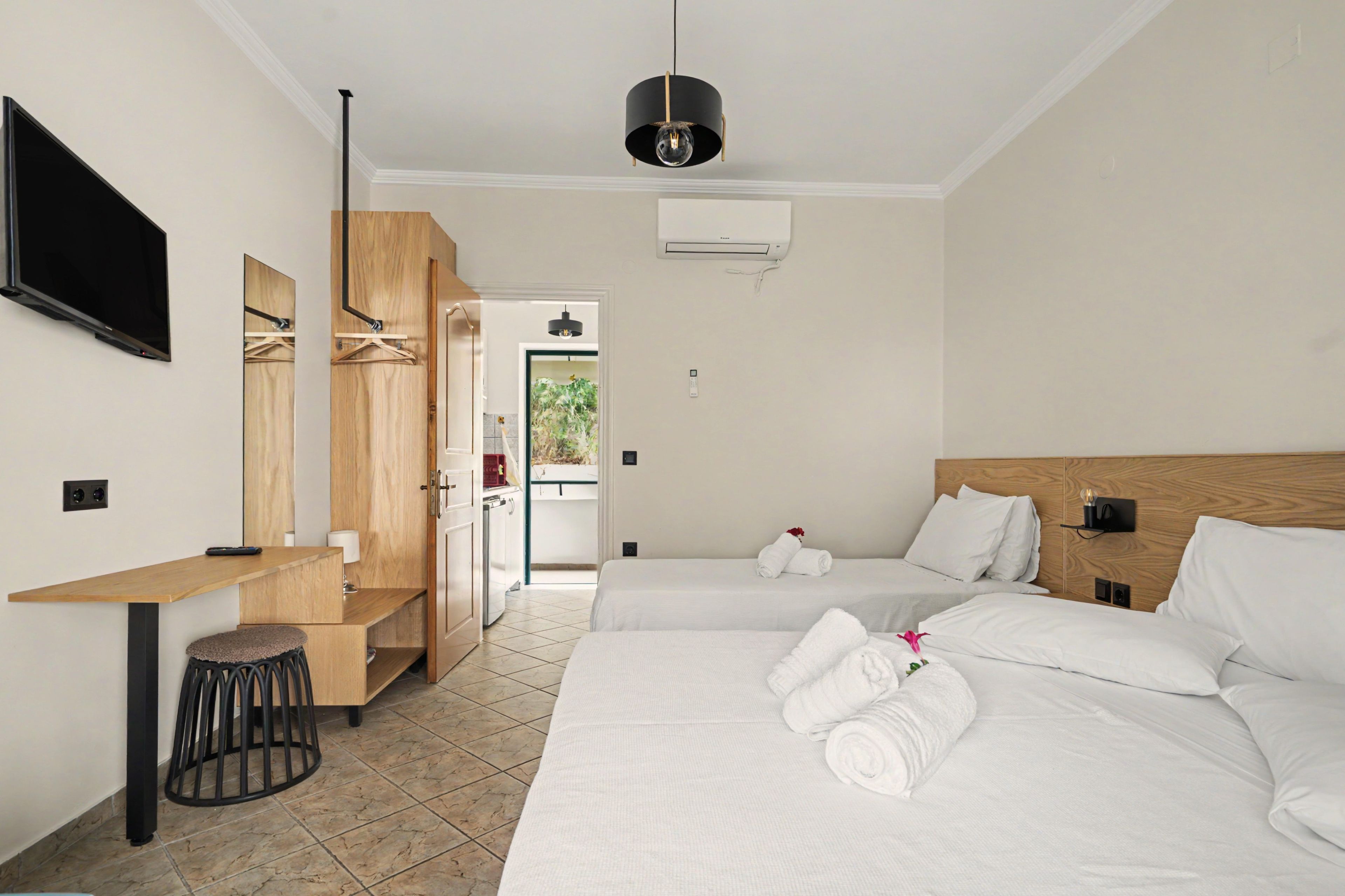 Una habitación de hotel con cama, escritorio, televisor y armario.