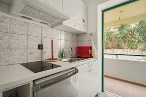 A kitchen with a dishwasher, a red drying rack, and a window with a view of greenery. - Deluxe Triple Room 5 Apartment with Mountain View, Wi-Fi, and Air Conditioning (Lefkada Municipality)
