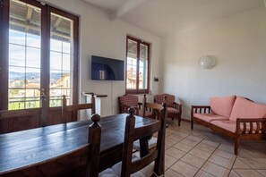 Un coin repas avec une table et des chaises en bois, un canapé et un téléviseur fixé au mur.
