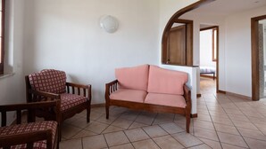 Un saló amb un sofà, cadires i un llum penjant a la paret.
