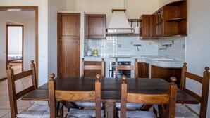 Una cuina amb armaris de fusta, taula de dinar amb cadires i respatller de rajola.