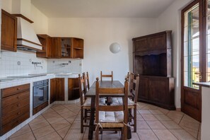 A kitchen with wooden cabinets, a dining table with chairs, and a window with a view. - [Appartamento Roberta] 5 beds + A/C (Santo Stefano di Magra)