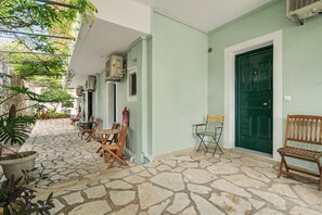 A building with a stone-paved courtyard, wooden furniture, and a green door. - One Bedroom Apartment 10 with Garden View, Wi-Fi, and Air Conditioning (Lefkada Municipality)