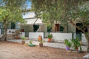 A courtyard with a white building, green shutters, and potted plants. - One Bedroom Apartment 10 with Garden View, Wi-Fi, and Air Conditioning (Lefkada Municipality)