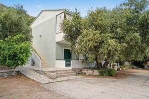 Um edifício de dois andares com uma escadaria de pedra que leva a uma porta verde.