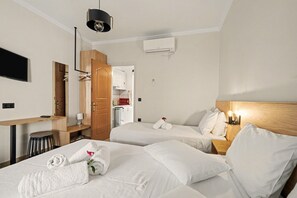 Ein Hotelzimmer mit zwei Betten, einem Schreibtisch, einem Fernseher und einem Kleiderschrank.