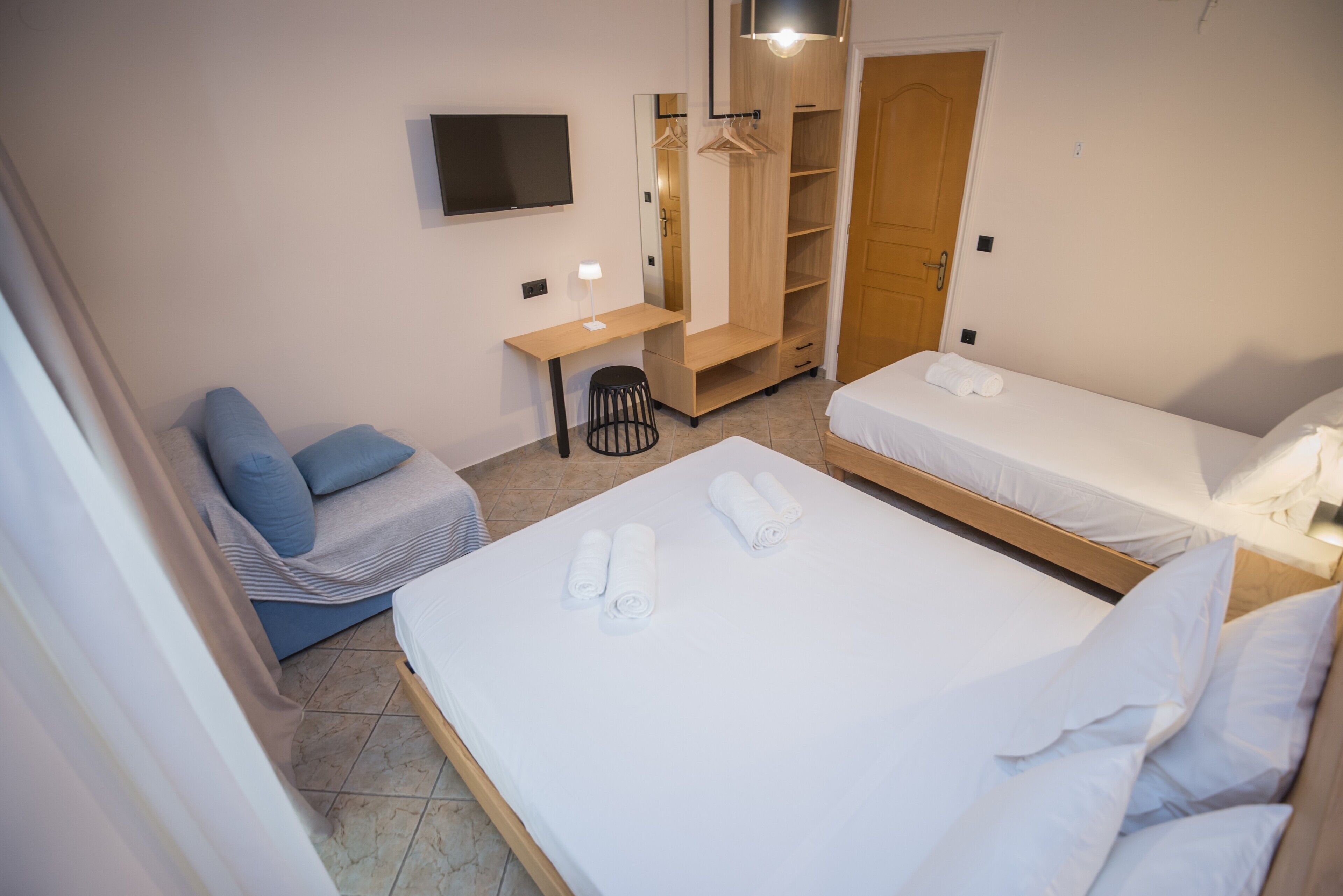 Ein Hotelzimmer mit einem Bett, einem Schreibtisch, einem Sessel, einem Fernseher und einem Kleiderschrank.