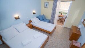 Quarto com duas camas, um sofá pequeno, uma mesa e uma cadeira.