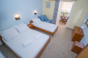 Ein Zimmer mit zwei Betten, einem kleinen Sofa, einem Tisch und einem Stuhl.