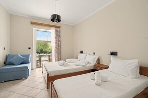Une chambre d’hôtel avec deux lits, un canapé, une table et une vue sur la verdure.