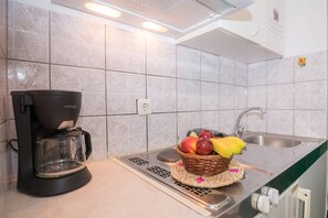 Eine Küche mit Kaffeemaschine, Obstkorb und Spüle.