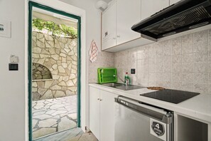 A kitchen with a stone wall, a green basket, a sink, and a dishwasher. - One Bedroom 9 Apartment with Garden View, Wi-Fi, and Air Conditioning (Lefkada Municipality)