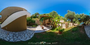 Ein Innenhof mit Steinmauer, einer Pergola und einem Grillbereich.