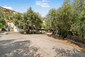 A paved courtyard with a staircase leading to a building, surrounded by trees and a wooden fence. - One Bedroom 9 Apartment with Garden View, Wi-Fi, and Air Conditioning (Lefkada Municipality)