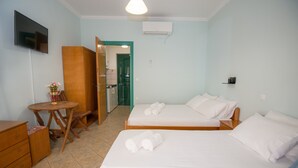 Habitación de hotel con dos camas, un escritorio, una silla, un televisor y una puerta que da al baño.