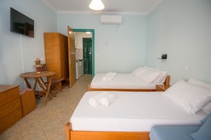 Ein Hotelzimmer mit zwei Betten, einem Schreibtisch, einem Stuhl, einem Fernseher und einer Tür zum Badezimmer.