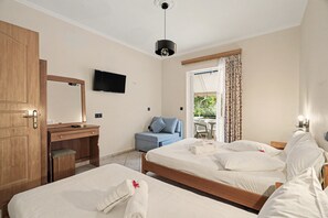 Habitación de hotel con dos camas, un escritorio, televisor y vistas al exterior.