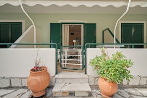 A building entrance with a staircase leading to a door, flanked by two potted plants. - One Bedroom 8 Apartment with Garden View, Wi-Fi, and Air Conditioning (Lefkada Municipality)