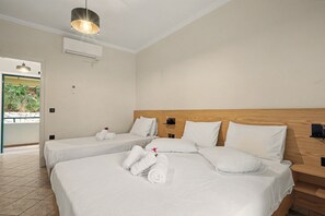 Ein Hotelzimmer mit zwei Betten, einem Holz-Kopfteil und Blick auf Grünflächen.