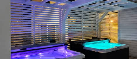 An outdoor hot tub area with a pergola structure and sliding blinds.