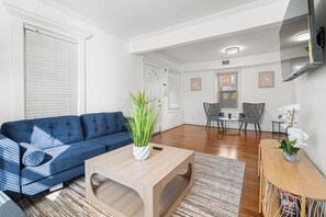 Ein modernes Wohnzimmer mit einem blauen Sofa, einem Holztisch und einem Essbereich inklusive Tisch und Stühlen.