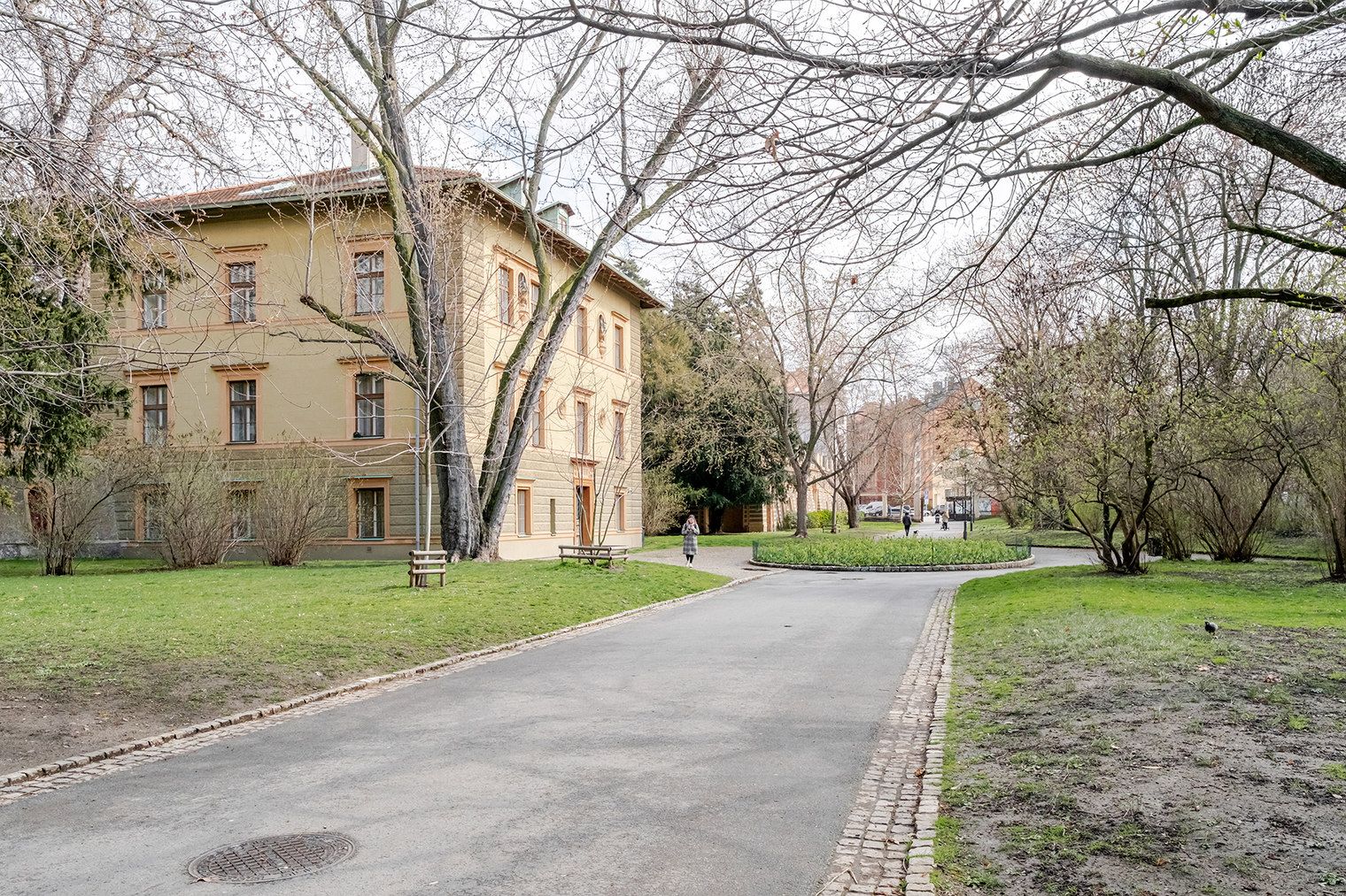 A paved pathway leading to a building with multiple windows and a central entrance.