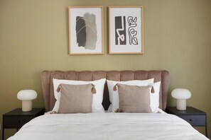 A neatly made bed with white bedding and two pillows, a brown upholstered headboard, and two bedside tables with white lamps. - Blueground Grebovka, Terrace, pet Friendly (Prague)