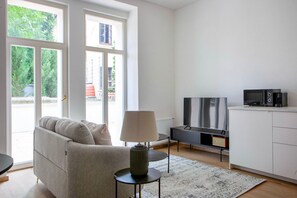 A modern living room with a sofa, a TV, a coffee maker, and a small table. - Rostovská Residence by Blueground (Prague)