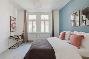 Ein modernes Hotelzimmer mit einem großen Bett, einem Schreibtisch und Blick durch große Fenster nach draußen.