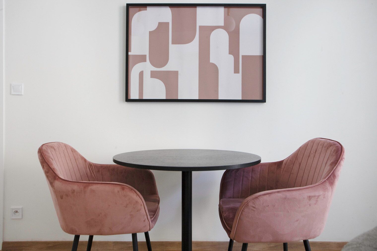 Ein Zimmer mit einem runden Tisch und zwei rosa Stühlen.