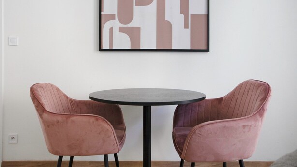 Quarto com uma mesa redonda e duas cadeiras cor-de-rosa.