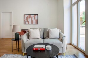 Ein Wohnzimmer mit grauem Sofa, einem schwarzen Couchtisch, einer Lampe und einem gerahmten abstrakten Kunstwerk an der Wand.
