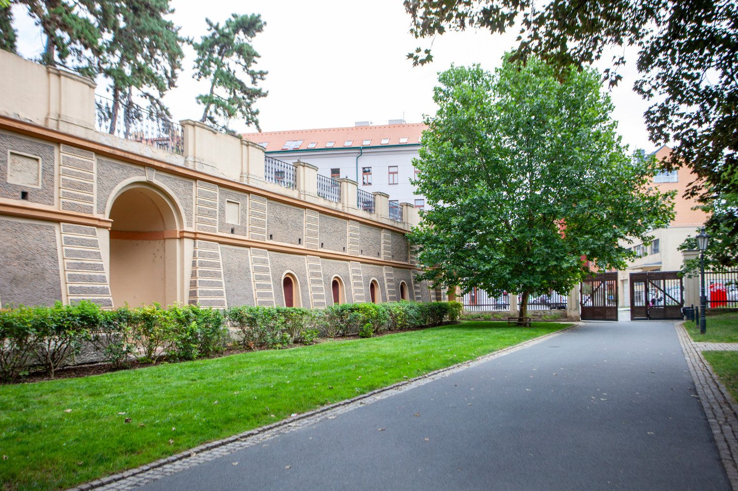 Un bâtiment doté d’un long passage couvert, de fenêtres en arc de cercle et d’un chemin bordé d’arbres.