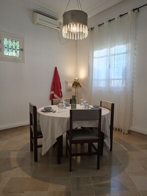 Ein Essbereich mit einem runden Tisch, Stühlen, einer Kandelaber und einem Fenster mit Vorhängen.