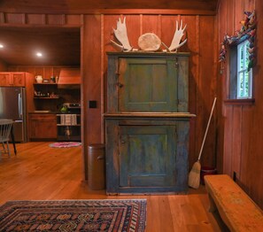 A rustic wooden interior with a large cabinet, a broom, and a rug. - Historic 3-BR cottage on coveted Megunticook Lake with AC/heat in Camden ME. (Camden)