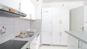 Une cuisine moderne avec des armoires blanches, un évier en acier inoxydable et un four à micro-ondes.