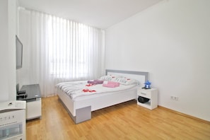 A bedroom with a bed, bedside table, and a desk with a chair.