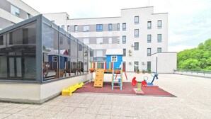 Un espace de jeux pour enfants avec un toboggan, des structures d’escalade et une balançoire.