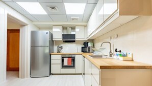 A modern kitchen with a stainless steel refrigerator, a microwave, and a built-in oven. - Quiet 2BR Haven Steps from The Greens Lakes and Emirates Golf Club,Al Dhafrah 2 (Dubai)