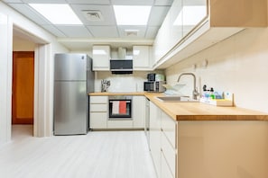 Eine moderne Küche mit einem Edelstahl-Kühlschrank, einer Mikrowelle und einem eingebauten Backofen.