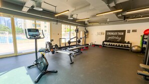 Un gimnasio con equipo de cardio, máquinas de pesas y un cartel motivacional.