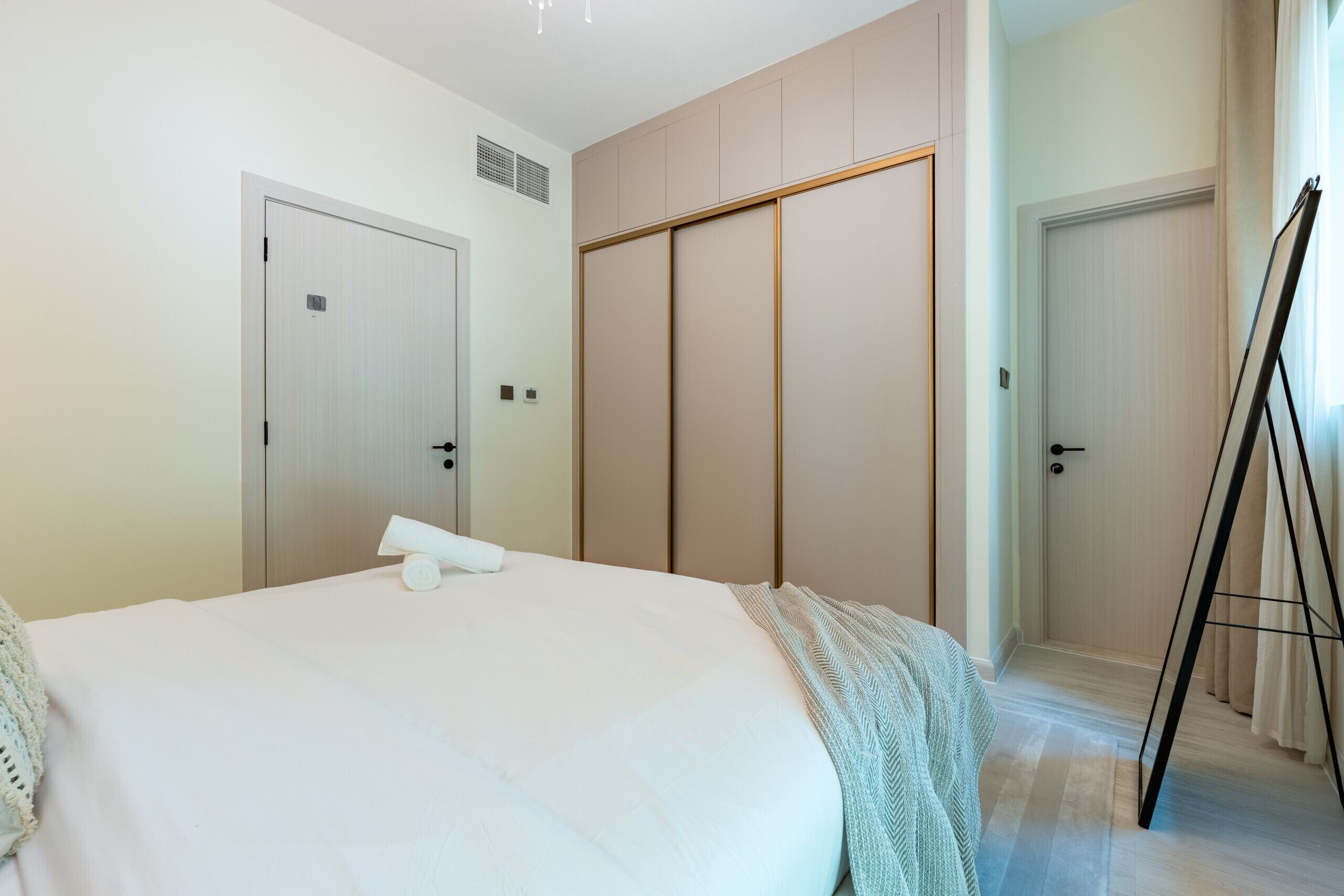 Hotellihuone, jossa on suuri sänky, vaatekaappi ja peili.