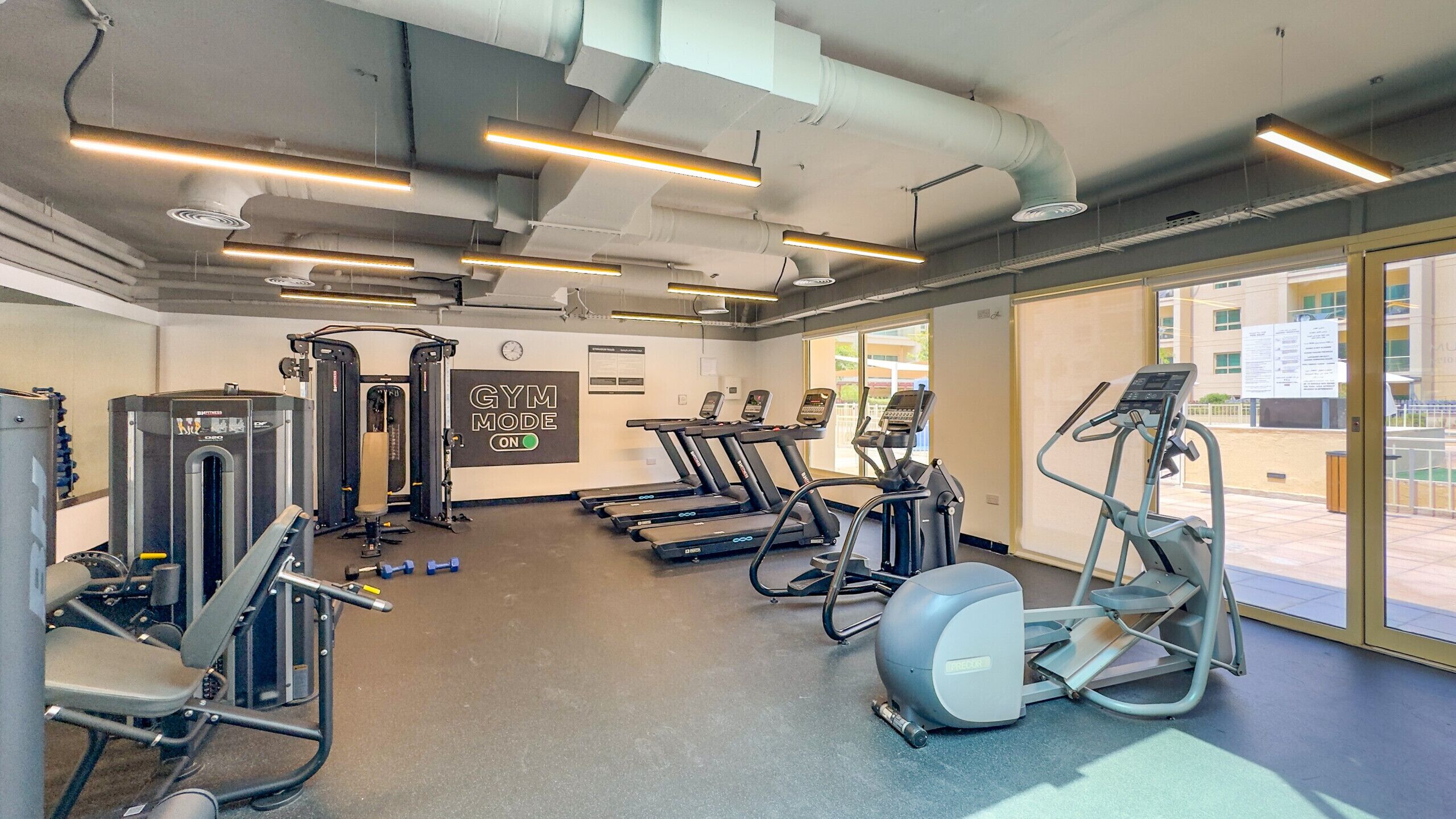 Une salle de sport équipée de tapis de course, de vélos elliptiques et de matériel de musculation.